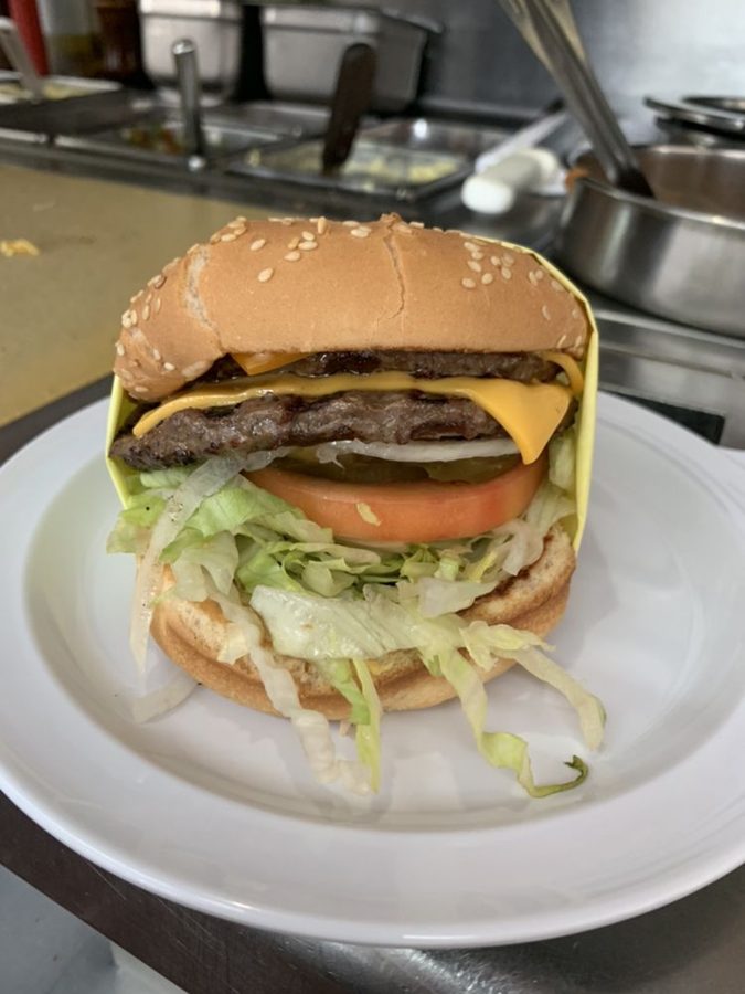 Double cheeseburger with lettuce and tomato on a plate at the kitchen counter