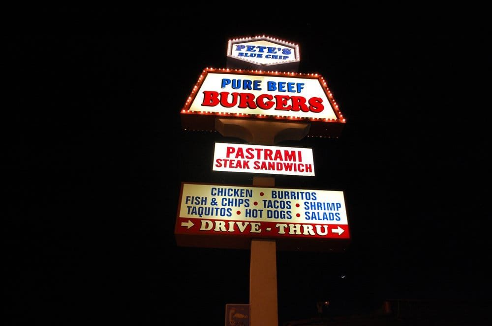 Pete's Blue Chip vintage pole sign lit up at night: Pure Beef Burgers, Pastrami Steak Sandwich, Drive-Thru